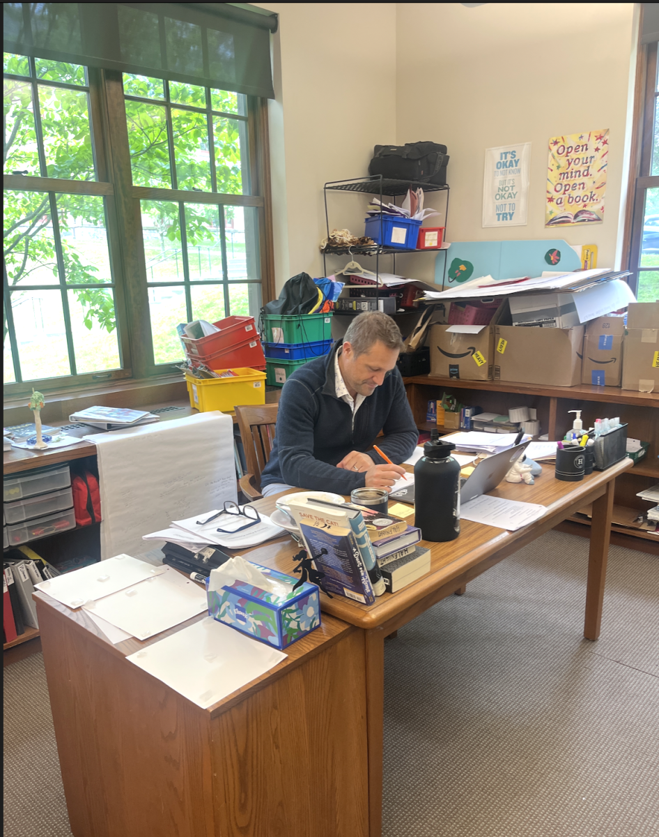 Mr. Halfnight sits working in his middle school classroom. Through teaching Middle School English, he has grown to love teaching students about different texts and how to write. 